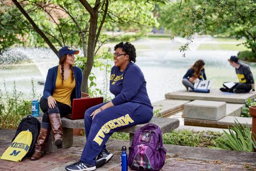 UM-Dearborn students sitting and talking by the Chancellor's pond