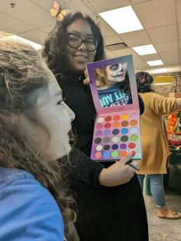 Photo of Rebekah Tuxbury, age 7, getting her face painted by Brianna Bryant.