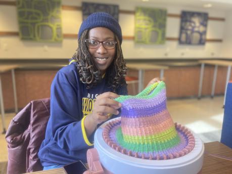 Photo of Henry Ford College student knitting a hat during the MLK Day of Service
