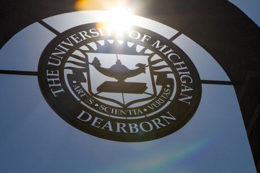 UM-Dearborn seal on building with sun shining through it.