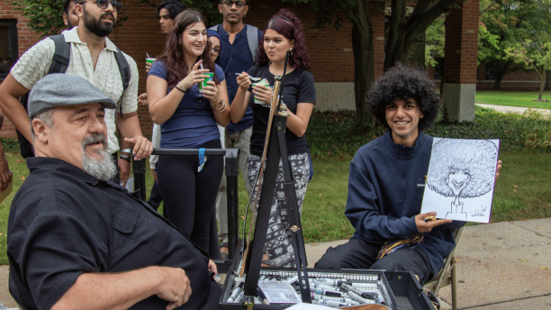 Student poses with a caricature drawing at the Go Blue Bash.