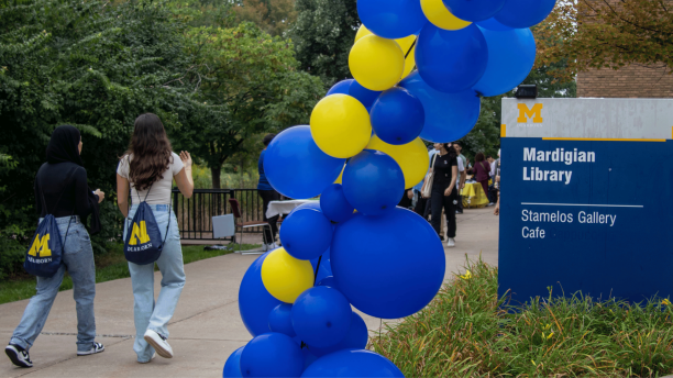 Students walk near a maize and blue balloon arch at the Go Blue Bash.