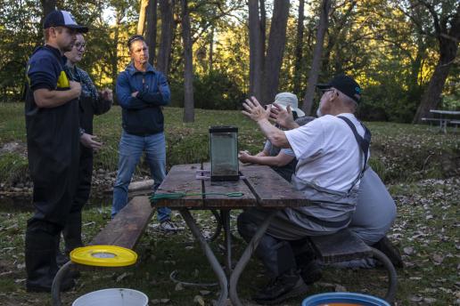 students and professor talking at outdoor picnic table