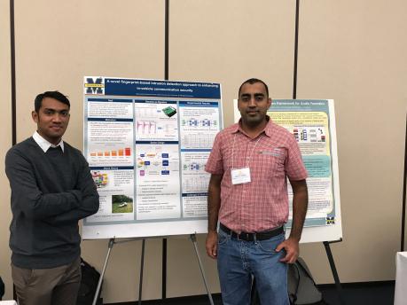 2 students standing on either side of their research poster