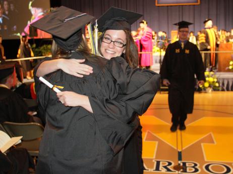 Student receiving a congratulatory hug from another student during Commencement