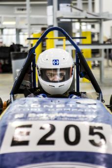 Student sitting in SAE race car wearing helmet
