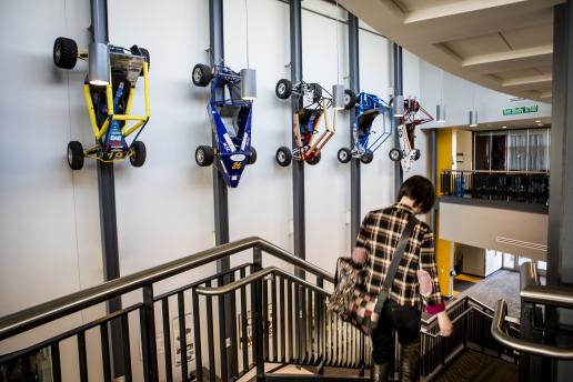 Model cars line the wall of the staircase with someone walking down stairs