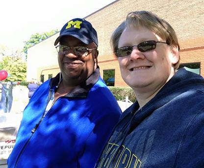 2 staff members. 1 wearing a Michigan hat and the other a Michigan sweatshirt.