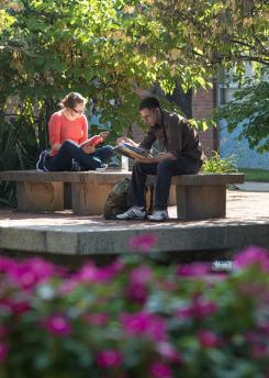 2 students reading sitting by the Chancellor's pond on a beautiful Spring day