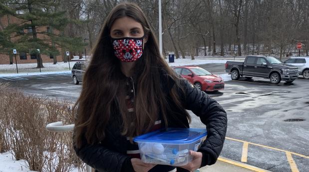 Woman with face mask holding a tupperware kit
