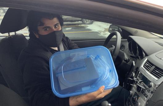 Student in driver's seat of car masked showing his kit