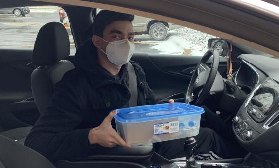 Student in driver's seat holding tupperware kit