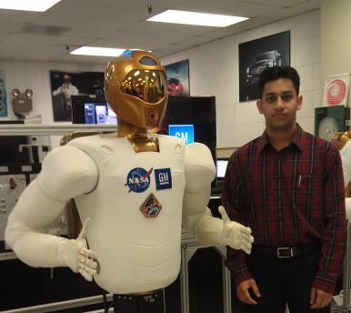 Student standing next to human like robot display logos of NASA and General Motors