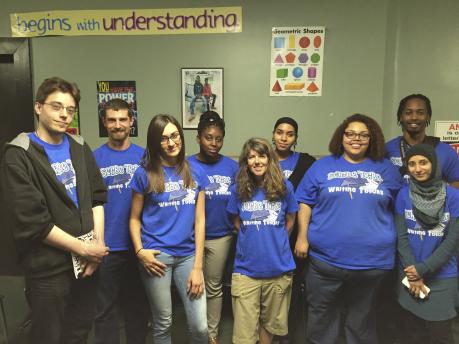 Group of students wearing blue shirts with a sign above them that reads "begins with understanding"