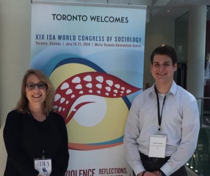 2 people standing in front of sign that reads: Toronto Welcomes XIV ISA World Congress of Sociology