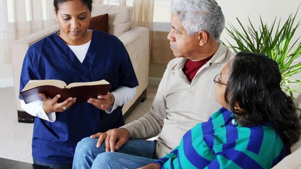 Older couple meeting with nurse reading from a book