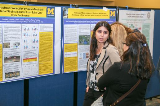 Student sharing research in front of her poster.