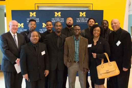 Group of students and Chancellor standing in front of UM-Dearborn Victors for Michigan background