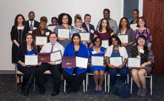 2 rows of people sitting/standing holding certificates