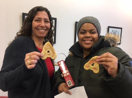 2 women holding cookies in the shape of the letter A