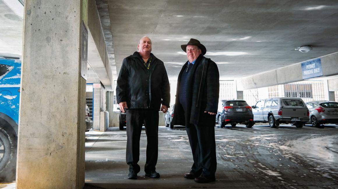 Jerry Van Couwenberghe and Kevin Headrick stand in a half empty parking garage on a cold winter day on the UM-Dearborn campus.
