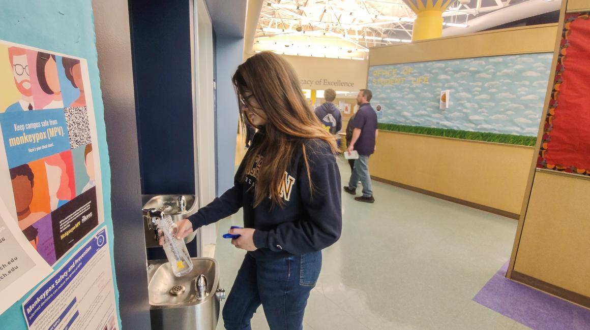 A student fills up a reusable water bottle at a bottle filling station on campus