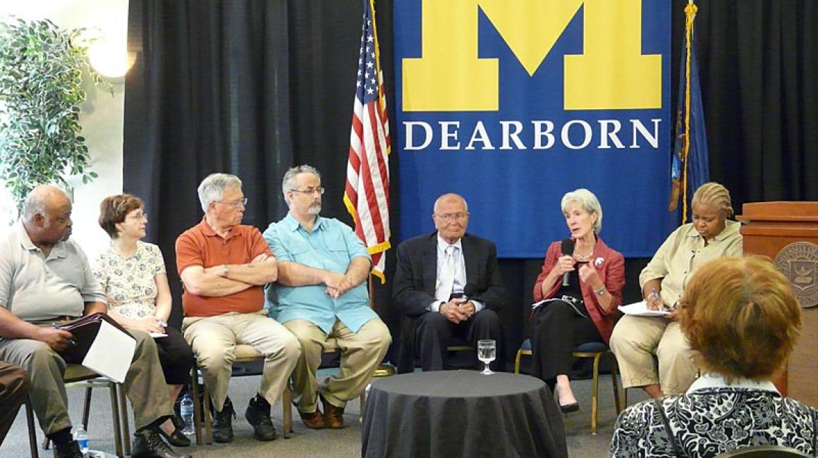 Rep. John Dingell and DHHS Secretary Kathleen Sebelius seated in a conference room with a group of senior citizens