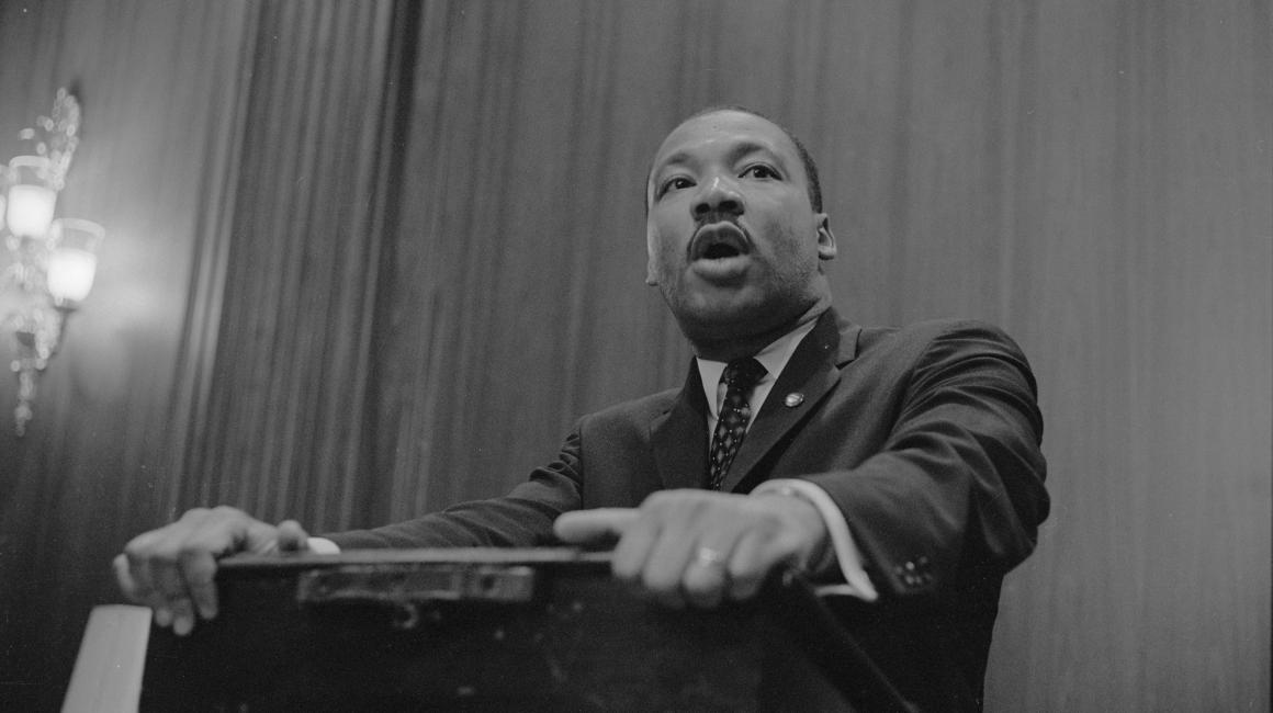 A portrait of Martin Luther King Jr. standing at a podium