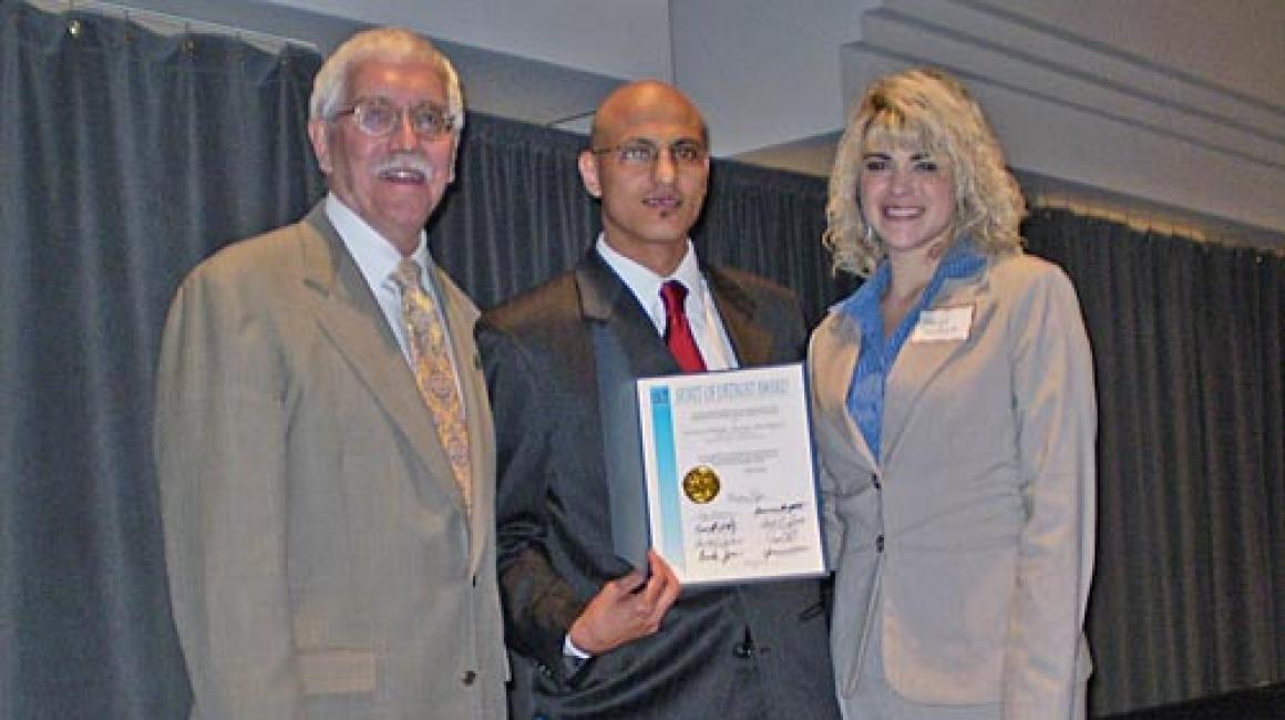 From left to right, accounting & finance lecturer Marshall Hunt; and accounting majors Ali A. Ali and Margo Souchock stand side by side holding a 'Spirit of Detroit' award