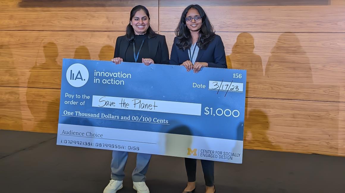 UM-Dearborn Kruthika Gopinathan and Richa Chachara hold up an oversized $1,000 novelty check at an awards ceremony