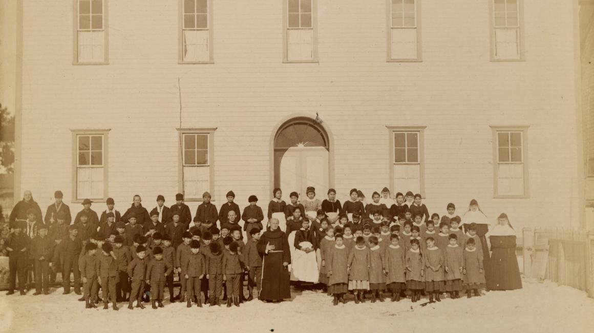  A historic photograph of Native American students standing outside Holy Childhood, an Indian Boarding School in Harbor Springs, Michigan that was one of the last to close in the United States. 