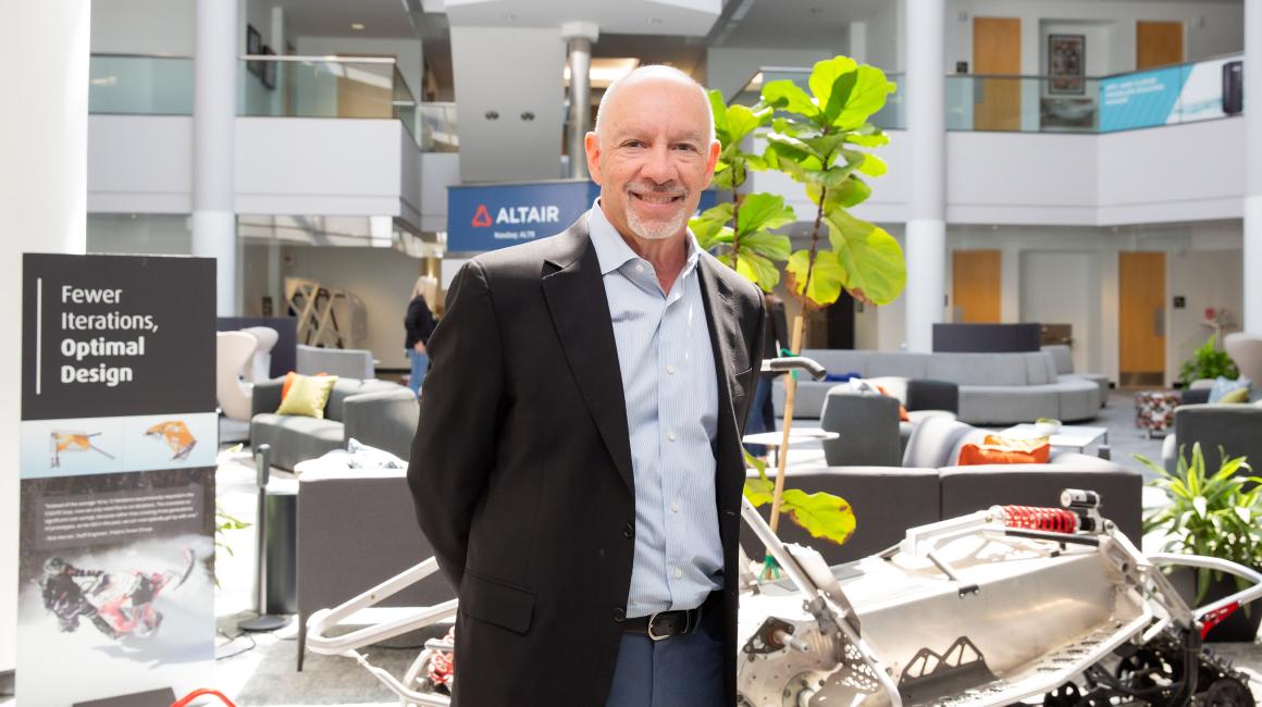 Jim Scapa stands for a portrait in the brightly lit lobby of his technology company Altair.