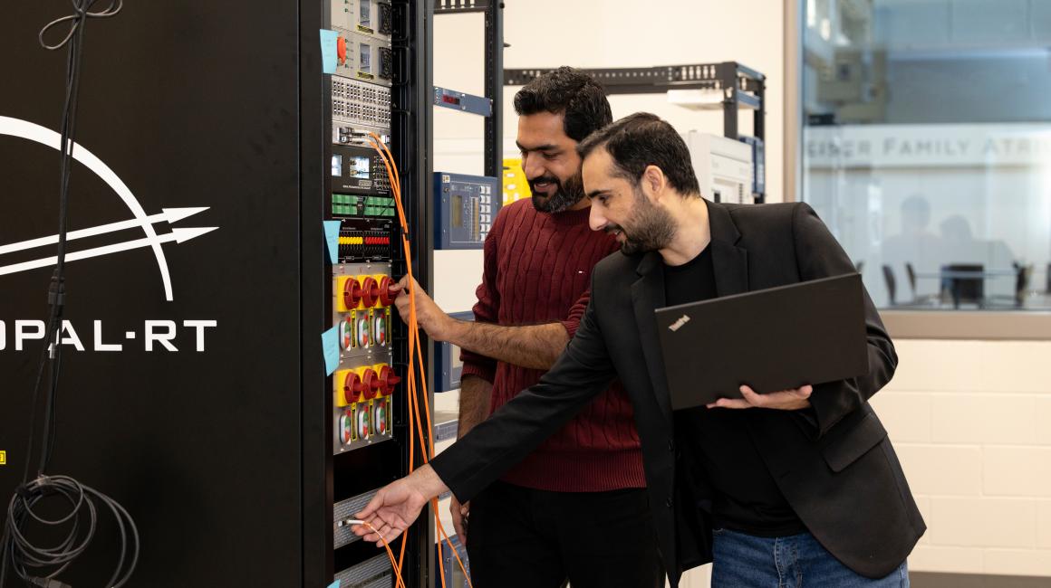 Doctoral students Ali Hassan (left) and Shahid Aziz Khan work with an OPAL-RT "hardware-in-the-loop" simulator in the lab of Professor Wencong Su. 