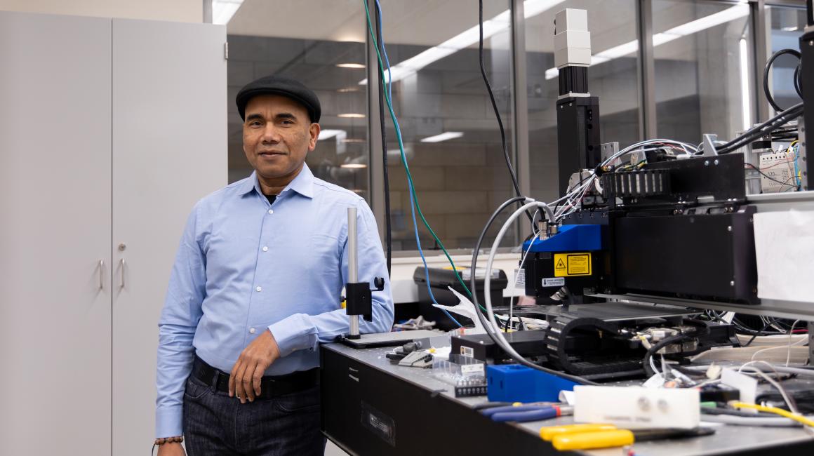 Wearing a black flat cap, Professor Pravansu Mohanty stands for a portrait in his mechanical engineering lab