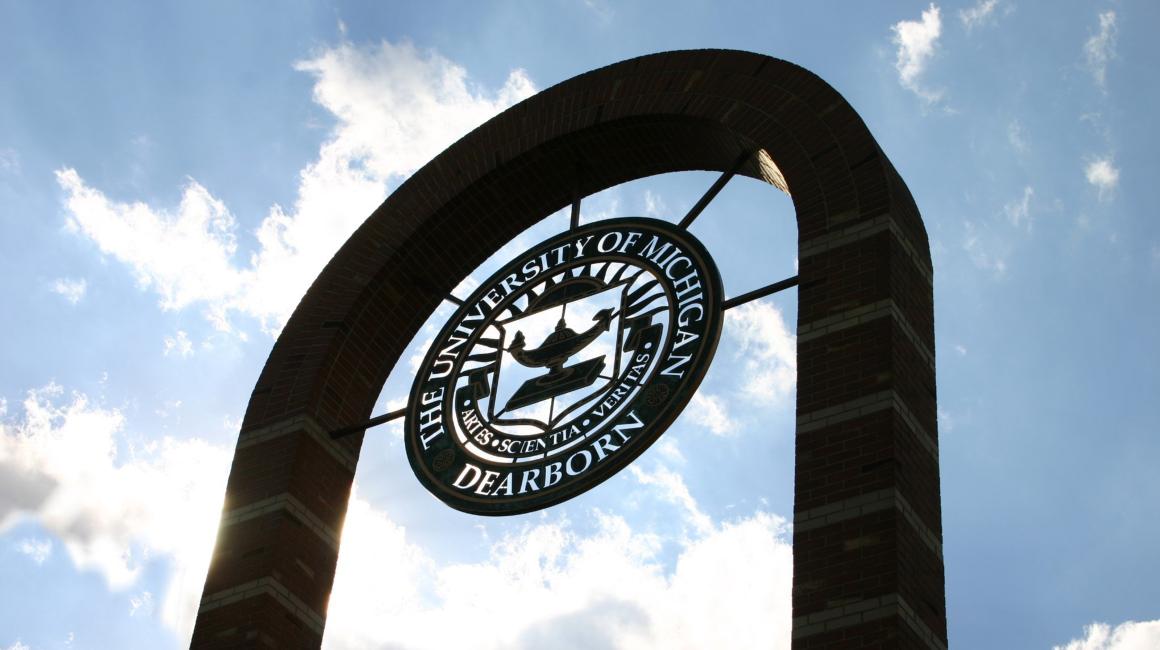 Looking upward toward brick arch containing the university seal on the UM-Dearborn campus on a sunny day