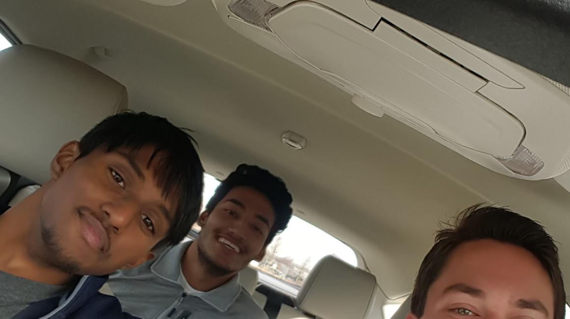 Three male students sitting in a car with a beige interior as part of a car-sharing study