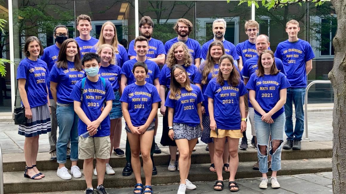 A group of students from the UM-Dearborn mathematics research experience. They are all wearing purple shirts with maize text reading, “UM-Dearborn Math REU 2021”