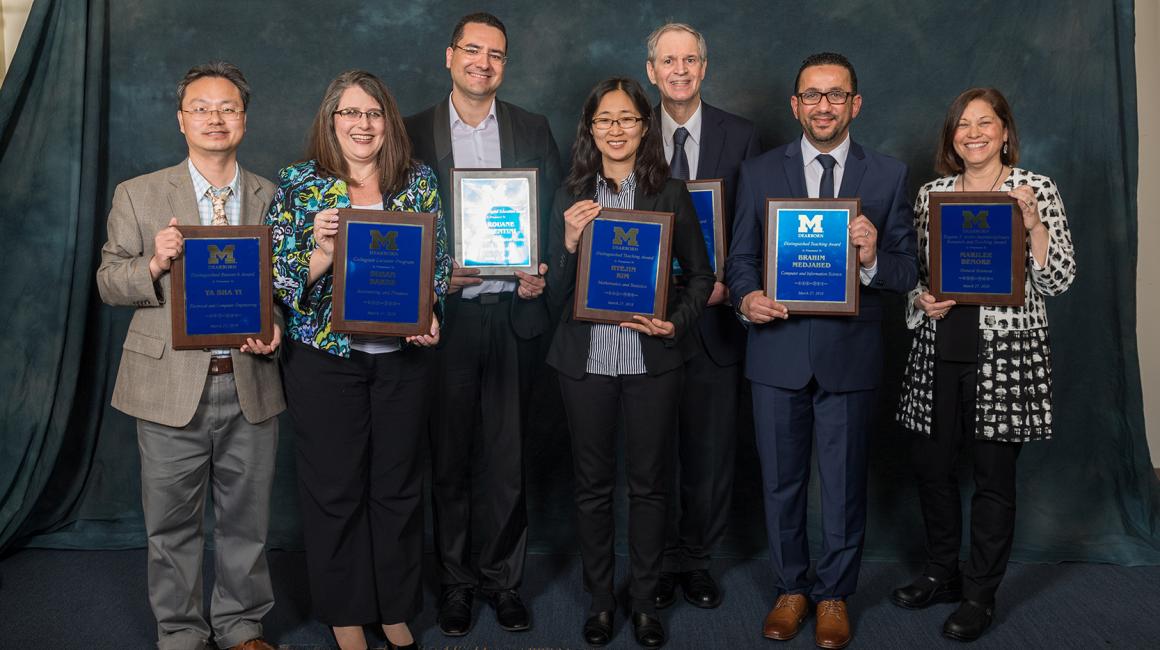 Ya Sha Yi, Susan Baker, Marouane Kessentini, Hyejin Kim, Frank Massey, Brahim Medjahed, and Marilee Benore all stand side by side. They are each holding a Faculty Award plaque.