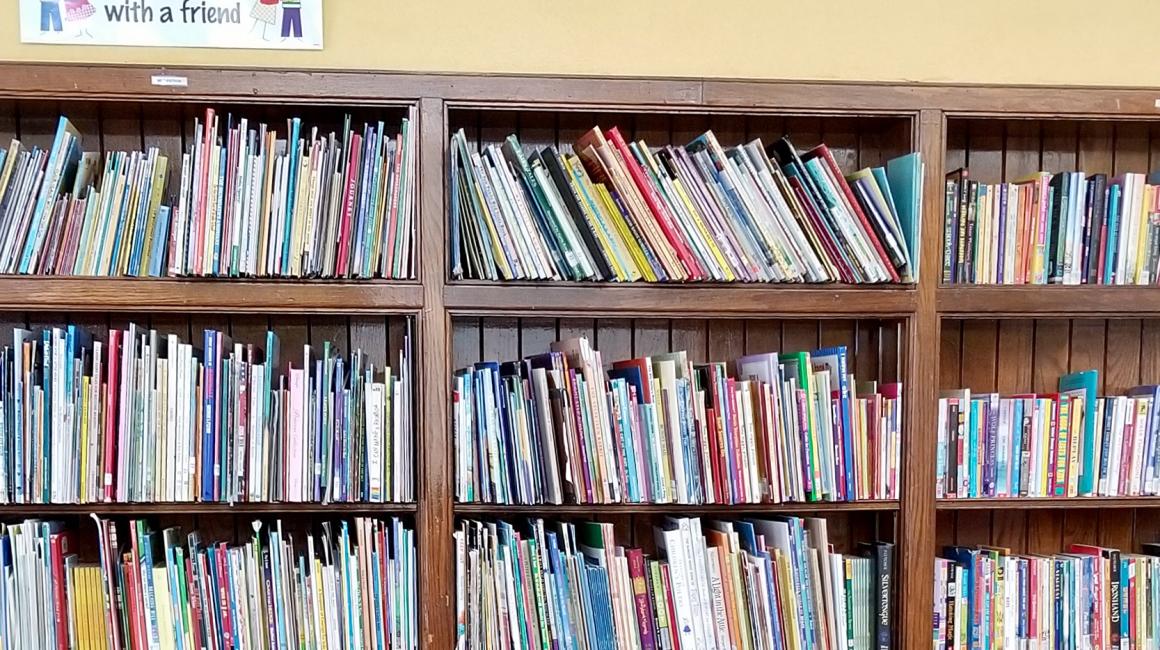 A few rows of bookshelves in the Bennett Elementary School Library filled with a variety of colorful children's books.