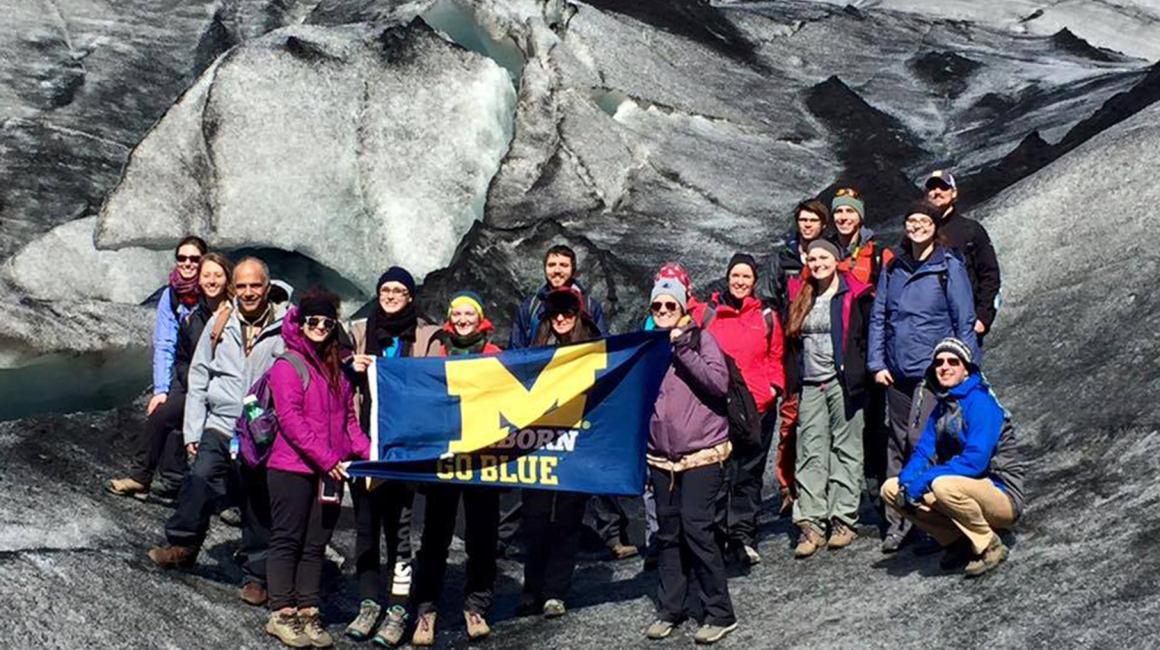 Students holding UM-Dearborn Go Blue flag in Iceland