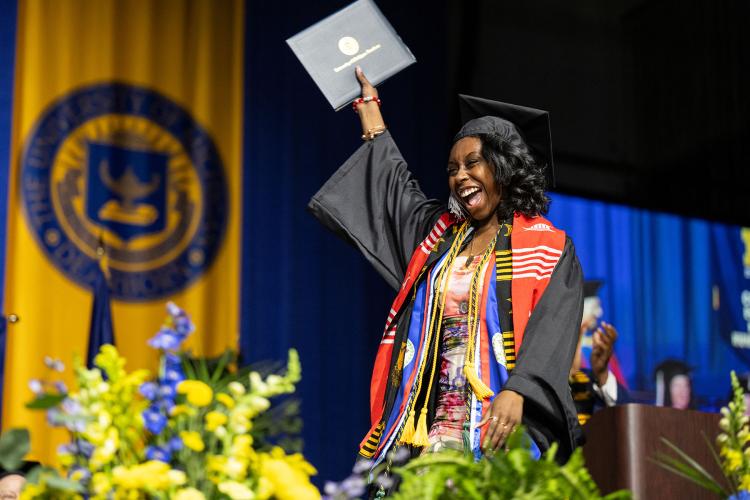 Graduant celebrating on stage during commencement ceremony