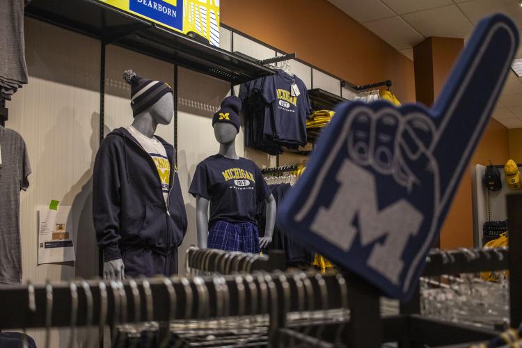 In the bookstore, sweatshirts and winter caps sit on mannequins, with a Block M foam finger in the foreground.