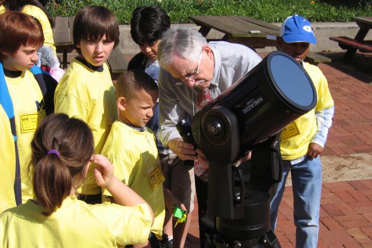 Instructor setting up telescope outside for group of children to see