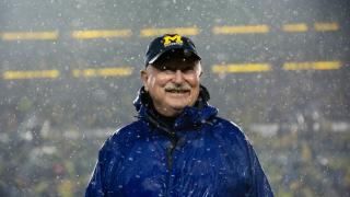 Tony England smiles, while standing in the snow at Michigan Stadium, wearing a UM-Dearborn ball cap.