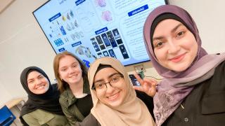 Four students from a senior design team pose for a selfie in front of their poster at Senior Design Day.