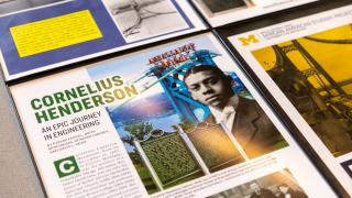 An angled shot of a poster board display featuring a historic photo of Cornelius Henderson, an image of the Ambassador Bridge and text about his life.